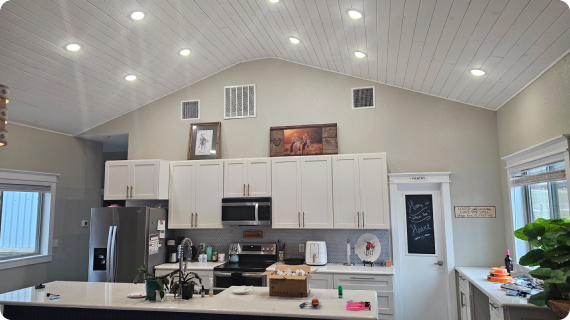 A kitchen with white cabinets and ceiling lights.