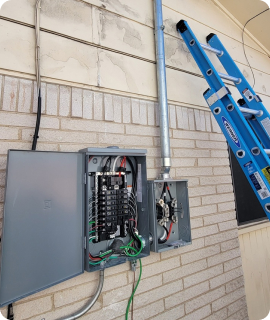 A ladder is attached to an electrical box on the side of a house.